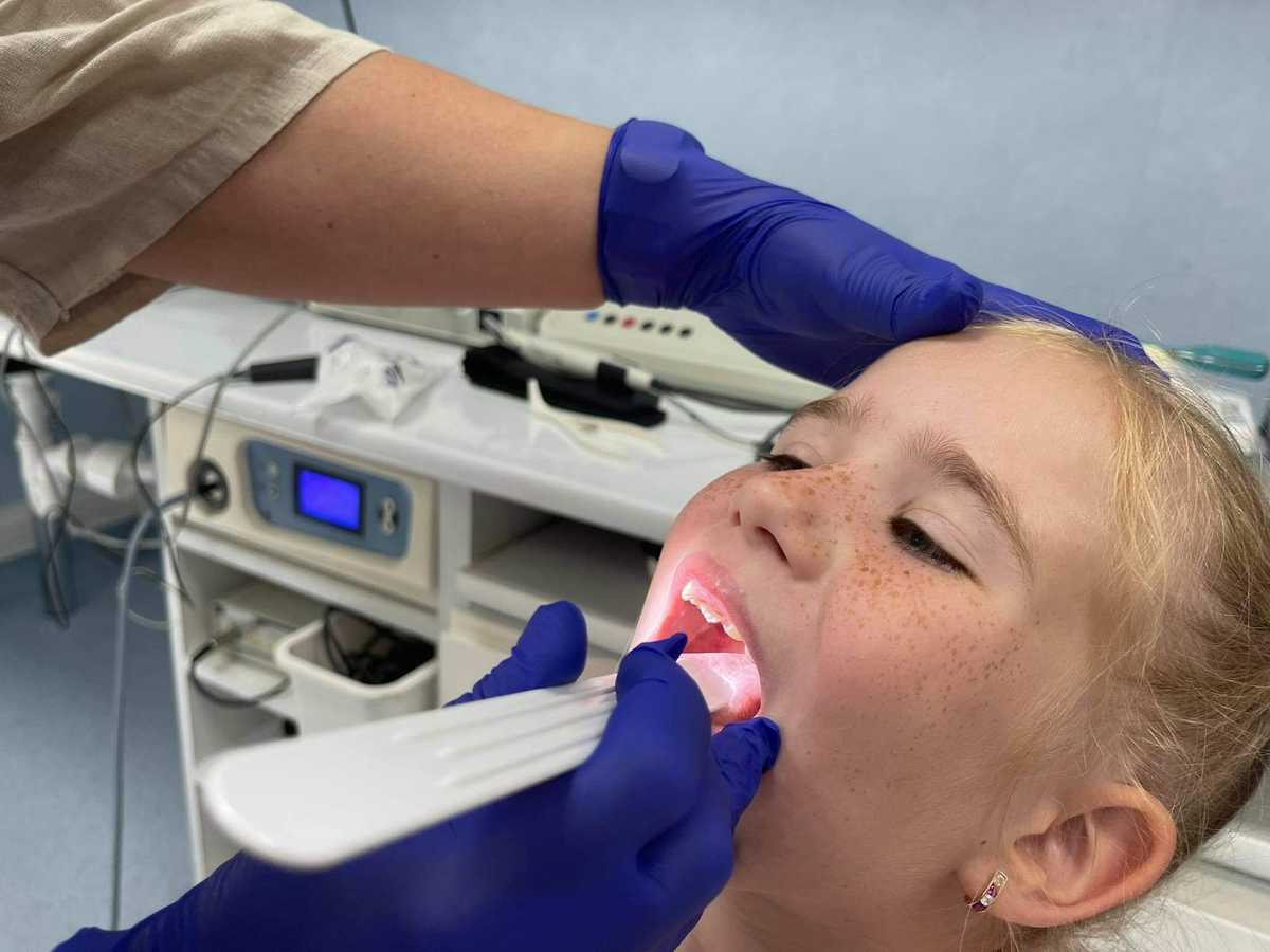 Zdjęcie dziewczynki, której gardło jest badane przez otolaryngologa