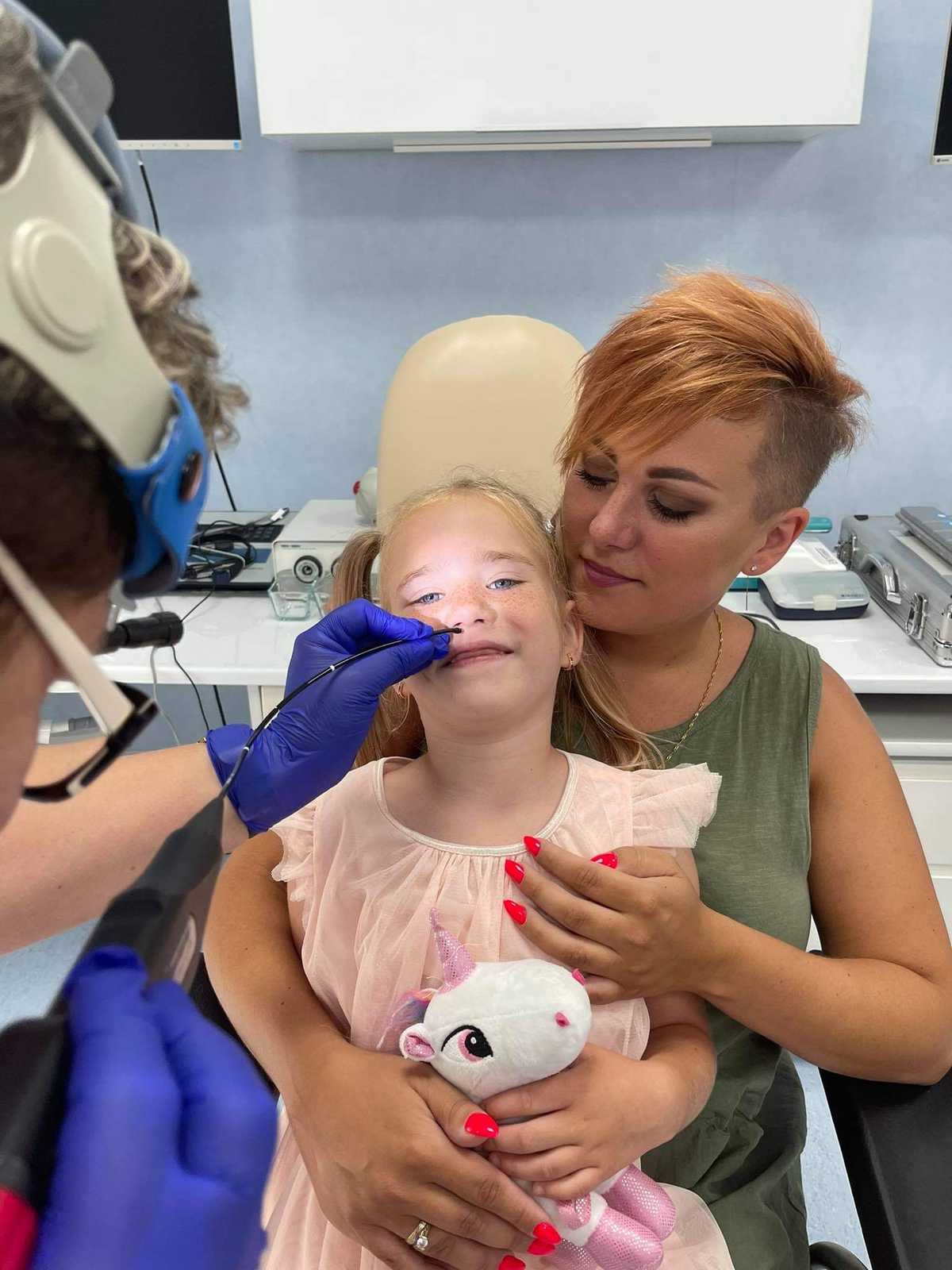 Zdjęcie dziewczynki, której gardło jest badane przez otolaryngologa nasofaryngoskopem